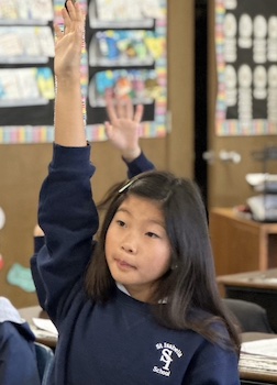 Student raising hand in classroom